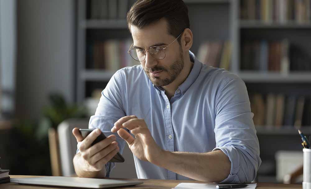 Mann schaut auf sein Smartphone und benutzt es