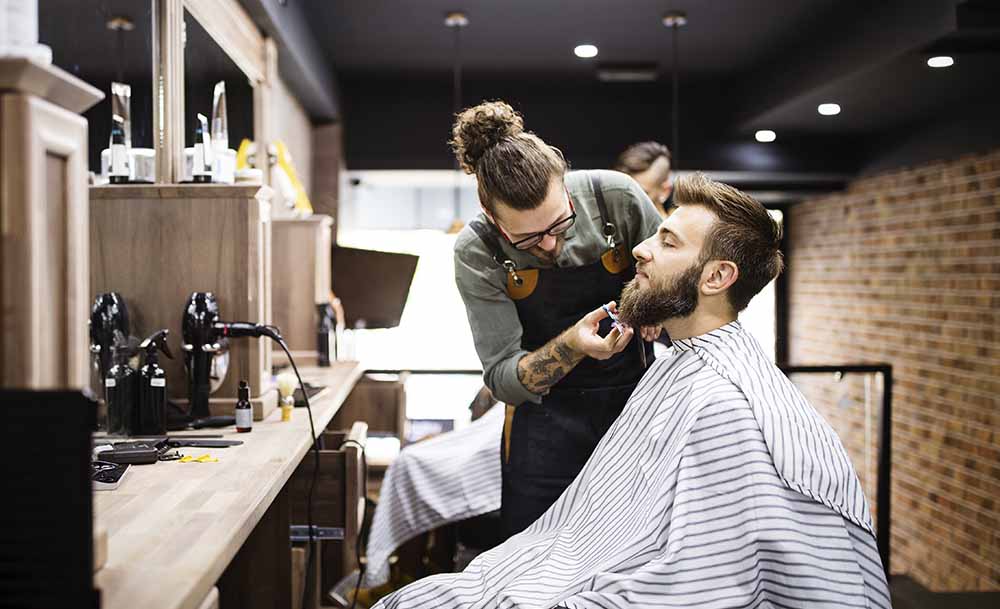 Friseur, der einen Kunden in seinen Geschäftsräumen betreut und rasiert