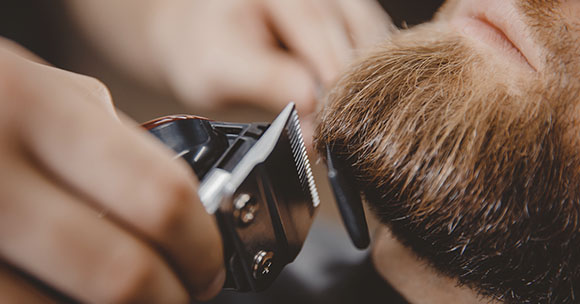 Barbier beim Trimmen des Bartes eines Kunden